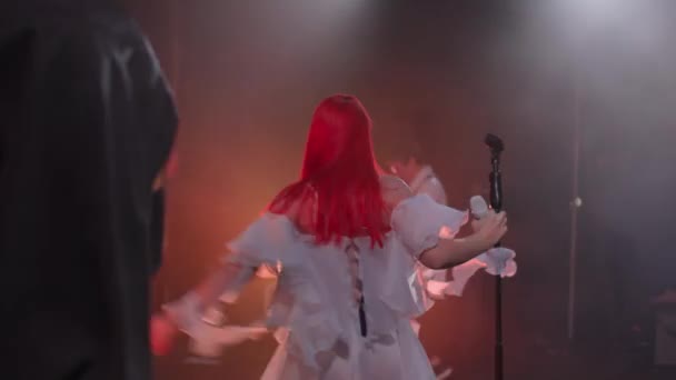 KHERSON, UKRAINE-SEPTEMBER 7, 2021: Festival Melpomene van Tavria, zangeres met rood haar treedt op het podium op met microfoon, meisje in een witte jurk zingt actief een lied tijdens een nachtconcert — Stockvideo