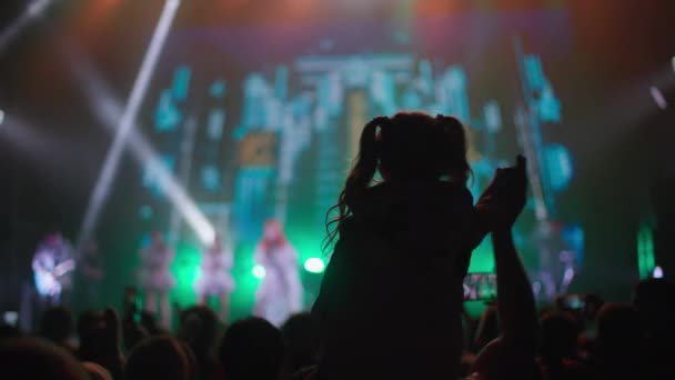 KHERSON, UKRAINE-ΣΕΠΤΕΜΒΡΙΟΣ 7, 2021: Φεστιβάλ Μελπομένης της Ταυρίας, κοριτσάκι που κάθεται στους ώμους του μπαμπά παρακολουθώντας συναυλία τη νύχτα, πλήθος κόσμου μπροστά στη σκηνή με πολύχρωμα φώτα και — Αρχείο Βίντεο