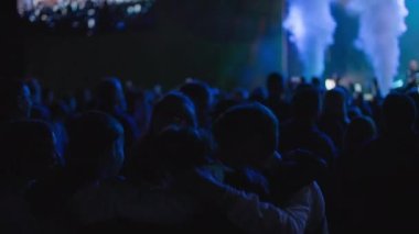 KHERSON, UKRAINE-SEPTEMBER 7, 2021: Tavria Melpomene Festivali, gençlerin birbirini kucaklaması, sahne ışıkları ve dumanla sahne arkasında konser kalabalığı içinde zıplaması