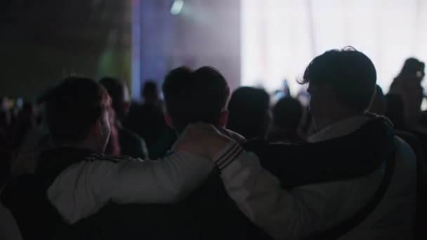 KHERSON, UCRANIA-SEPTIEMBRE 7, 2021: Festival Melpomene de Tavria, los jóvenes levantan las manos y saltan juntos sosteniéndose entre sí en multitud de conciertos contra el telón de fondo del escenario con proyectores en — Vídeo de stock