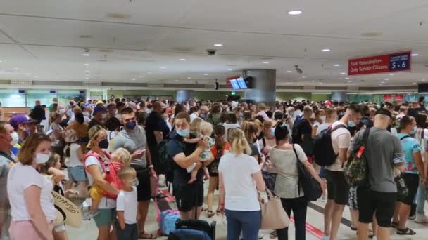 АНТАЛИЯ, ТУРЦИЯ - 21 июля 2021 года: огромная очередь во время пандемии внутри аэропорта, пассажиры стоят в очереди на проверку паспортов — стоковое видео