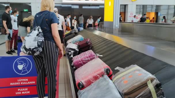 ANTALYA, TURKEY - 21 juli 2021: bagageutlämningsområde på internationella flygplatsen, maskerade människor väntar och hämtar sitt bagage från transportbandet — Stockvideo