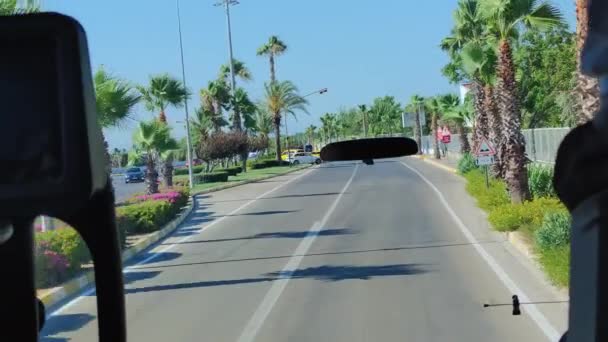 アンタルヤ、トルコ- 2021年7月21日:車やヤシの木がある道路上のバスからの眺め、晴れた日の自家用バスでの旅 — ストック動画