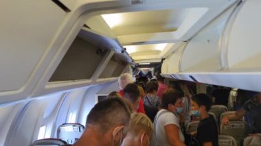 KIEV, UKRAINE - 31 Temmuz 2021: Uçak havaalanına vardı, salgın sırasında maskeli yolcular bavullarını alıp uçaktan indiler.