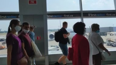 KIEV, UKRAINE - 31 Temmuz 2021: Coronavirus salgını sırasında maskeli insanlar havaalanındaki cam koridordan geçer