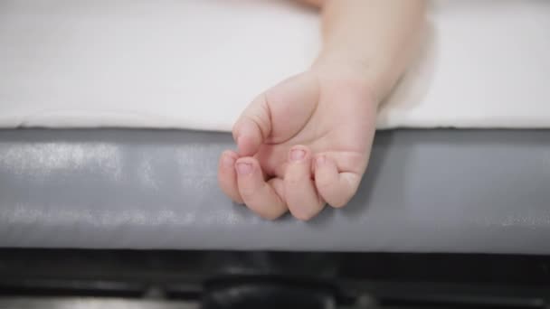 Здоров'я дитини, рука пацієнта маленької дитини під анестезією на операційному столі під час операції, крупним планом — стокове відео