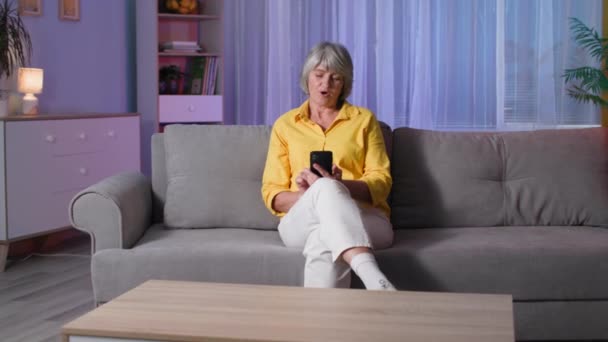 Seniorin benutzt Gadget, Portrait-Oma hält Handy mit grünem Bildschirm auf Sofa zu Hause, Leerraum für Layout — Stockvideo