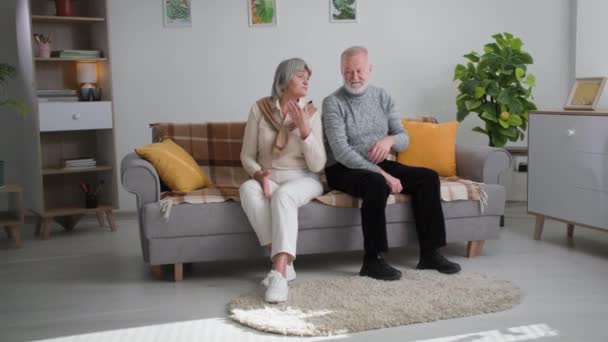 Crisis en las relaciones, cónyuges ancianos sentados por separado en el sofá, pareja de ancianos casados disputa en casa — Vídeo de stock