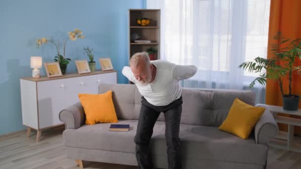 Αρθρίτιδα, ανθυγιεινό γέρος με πόνο στην πλάτη στέκεται δίπλα στον καναπέ, προβλήματα υγείας στους ηλικιωμένους συνταξιούχους — Αρχείο Βίντεο