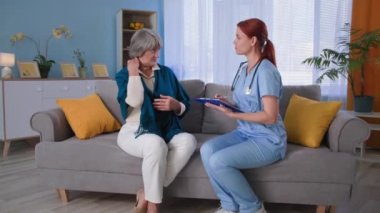Yaşlı ev bakımı, kadın terapist ve yaşlı kadın emeklilerin koltukta otururken tıbbi tedavi hakkında konuşmaları, doktor ve yaşlı hastanın portresi.