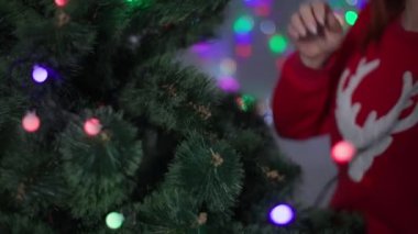 Kış tatilleri, suni Noel ağacı süsleyen bir kız evde çelenk, kırmızı kazaklı genç bir kadın Noel koşuşturmasının keyfini çıkar.