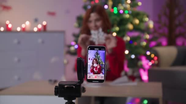 Homemade paper snowflake, female blogger remotely on camera of mobile phone tells how to make decor for new year near Christmas tree — Vídeo de Stock