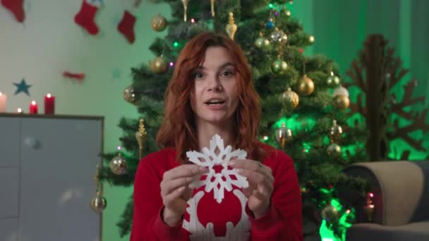 Online training on how to make paper snowflakes, young woman blogger talks about crafts for New Year interior while sitting at home near a Christmas tree, webcam view — Stok video