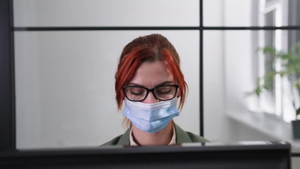 Tıbbi maske takan bir ofis çalışanının portresi tehlikeli virüsün yayılması nedeniyle modern güvenlik standartlarını gözlüyor, maskesini çıkarıyor, gülümsüyor ve kameraya bakıyor. — Stok video
