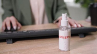 Kadın çalışanın masasında virüs ve enfeksiyona karşı yüzey tedavisi için pandemik ve antiseptik madde var.