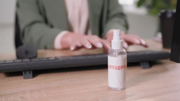 Büroangestellte tippt auf der Tastatur und behandelt Oberfläche mit Antiseptika, während sie im Büro arbeitet, nachdem sie Sperren entfernt hat — Stockvideo