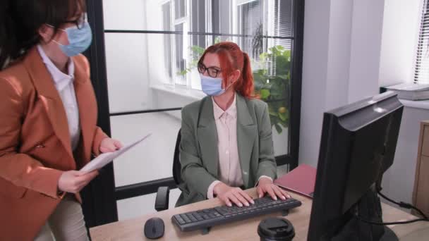 Молода жінка-працівник носить медичні маски для захисту від вірусу та інфекції вживає запобіжні заходи під час роботи на посаді — стокове відео