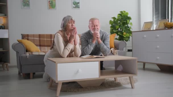 Religião, homens e mulheres aposentados com amor e esperança em seus corações a Deus orar em carruagem com as mãos dobradas juntas enquanto se ajoelham à mesa no quarto — Vídeo de Stock