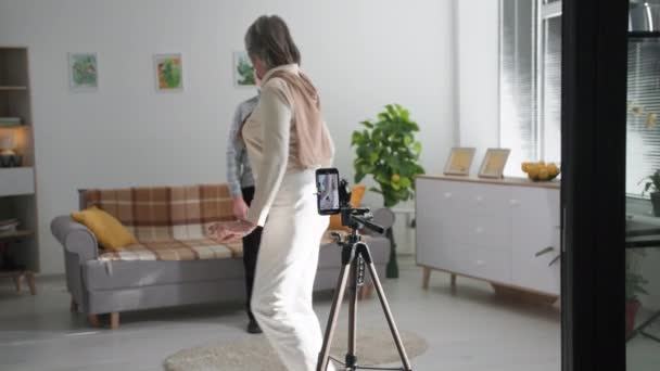 Passe-temps seniors, adorables retraités hommes et femmes s'amusent à filmer le contenu vidéo des médias sociaux sur une caméra de téléphone portable dans le salon de la maison — Video