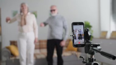 Blogcular, emekli yaşlı adam ve kadın akıllı telefon kamerasıyla video içeriği kaydediyor ve klas, yakın çekim