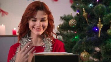 Noel tatili, güzel bir kadın bir kutu açar ve Noel ağacının yanında oturmaktan zevk alır.