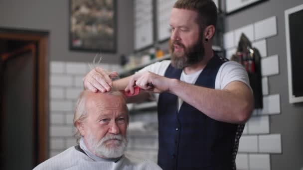 Słodkie starszy mężczyzna siedzi w a fryzjer fotelik podczas cięcia i fryzjer w a salon fryzjerski — Wideo stockowe