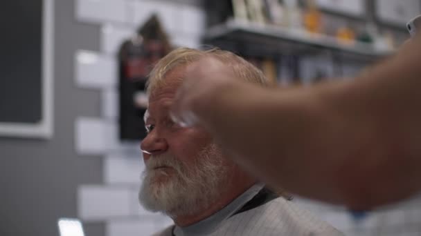 Elegante vecchio maschio in un salone da uomo ottenere taglio di capelli e styling presso un barbiere professionista in un salone di parrucchiere — Video Stock