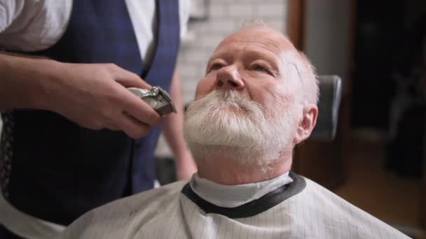 Salone da uomo, un anziano uomo che pulisce la barba e siede su una poltrona da barbiere professionista per parrucchiere — Video Stock
