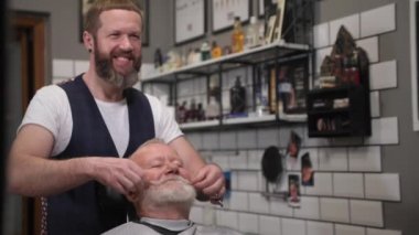 Profesyonel modern erkek kuaför kuaför kuaförü kuaförden kuaföre, kuaförden kuaföre, kuaförden kuaföre, kuaförden kuaföre, çekici yaşlı müşteriye, çekici, neşeli, yaşlı bir adama kesim ve şekillendirmeden sonra aynaya bakıyor.