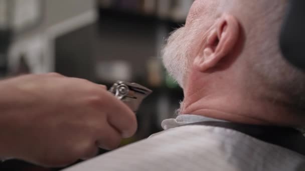 Friseursalon, männlicher Friseur verwendet einen professionellen Trimmer, um Bart und Schnurrbart für eine ältere Kundin zu trimmen, Nahaufnahme — Stockvideo