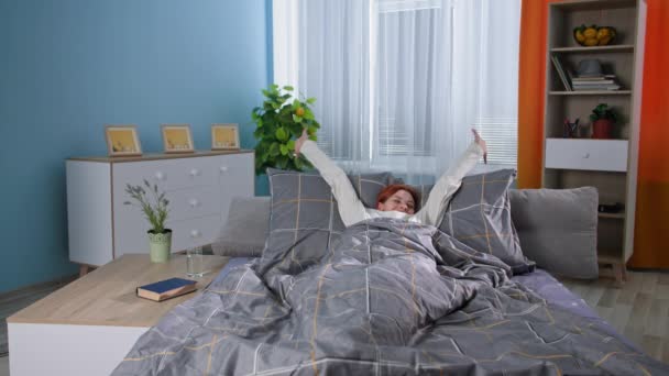 Gezondheidszorg, jonge gelukkige vrouw drinkt glas schoon water nadat ze wakker werd terwijl ze in bed zat in een gezellige kamer, lachend en kijkend naar de camera — Stockvideo