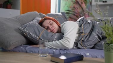 Günaydın, neşeli genç kadın uyandı ve yatak odasında yatarken temiz su içti. Gülümsedi ve kameraya baktı.