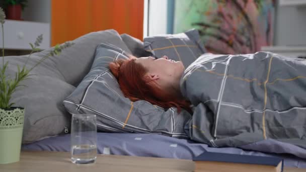 睡眠不足；由于身体不好或压力大而失眠的年轻妇女躺在房间的沙发上 — 图库视频影像