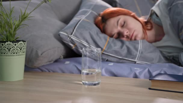 Wasserhaushalt, Glas mit Wasserhintergrund einer schlafenden Frau im Bett, Nahaufnahme — Stockvideo