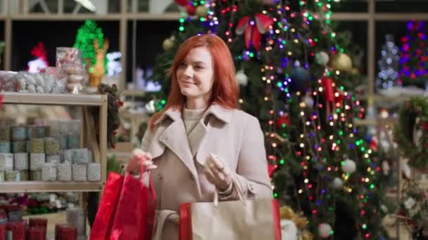 Рождественские подарки, домохозяйка выбирает подарок для семьи и друзей на зимний отдых в супермаркете фоне дерева — стоковое видео
