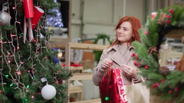 Kerstinkopen, vrouw kiest Nieuwjaar decoraties voor kunstmatige dennenboom in warenhuis — Stockvideo