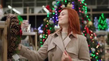 Yılbaşı tatiline hazırlanan genç bir kadın, evi alışveriş merkezindeki yeni yıl tatiline hazırlamak için güzel dekorasyonlar seçiyor.