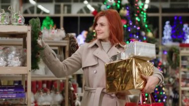 Noel alışverişi, elinde hediyelerle gülümseyen kadın alışverişçiler, alışveriş merkezinde tatil için ev dekorasyonu seçiyor.