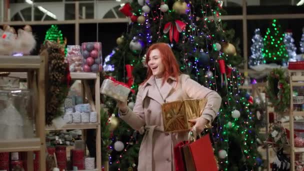 Nieuwjaar winkelen, vrolijke vrouwelijke shopper kiest geschenken en huisdecoraties in de supermarkt tijdens kortingen, glimlacht en kijkt naar de camera — Stockvideo
