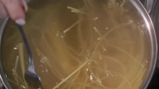 パスタは若い女性が鍋の中の湯でスパゲティを調理し — ストック動画