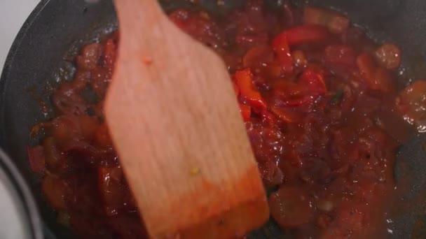 Cuisine maison, sauce tomate aux légumes est mélangée avec une spatule en bois dans une casserole de pâtes chaudes, gros plan — Video