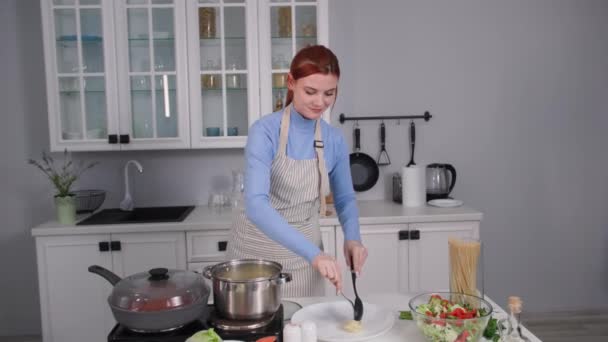 Cocina italiana, encantadora cocinera pone espaguetis en un plato para servir en la mesa mientras está de pie en la cocina — Vídeos de Stock