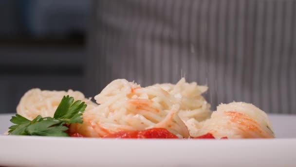 Macarrão italiano, espaguete delicioso com soja e decorado com verduras em um prato branco polvilhado com queijo parmesão ralado antes de servir durante o jantar, close-up — Vídeo de Stock