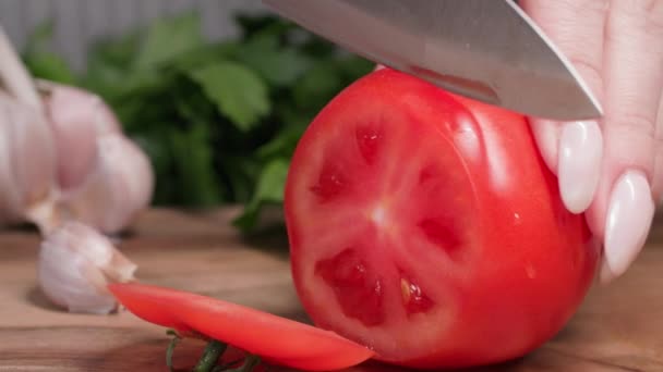 Nutriție adecvată, o femeie taie roșii suculente coapte cu un cuțit pe o placă de tăiere pentru a pregăti o salată vegană — Videoclip de stoc