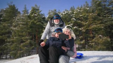 Aktif kış haftasonu, çocuk cep telefonuyla video çekiyor ve büyükannesiyle tepeden aşağı kayıyor, torunuyla birlikte emekli oluyor.
