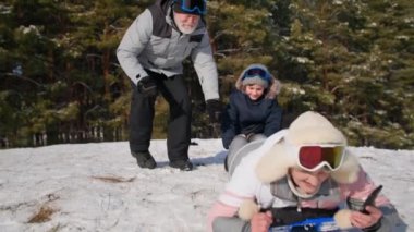 Aktif kadın emekliler kızakların üzerinde kayarak kayıyor ve cep telefonuyla video kaydı yapıyor. Dedeleri ve nineleri kış ormanlarında torunlarıyla eğleniyor.