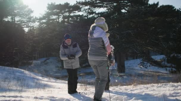 Šťastní prarodiče hrají sněhové koule s vnukem, starší pár s chlapcem aktivně tráví víkend v lese — Stock video