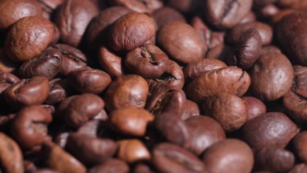 Fondo de granos de café tostados que caen de arriba mientras se fríen en una sartén, primer plano — Vídeo de stock