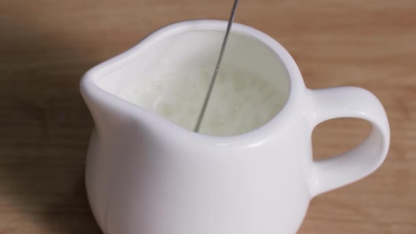 Delicious milk frothed with a manual cappuccinatore in a milk jug, close-up — Stock Video