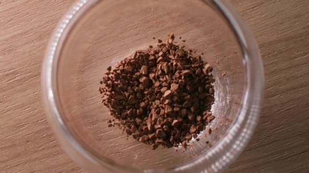 Close-up van instant koffie die wordt gegoten in een transparant dubbelzijdig glas, bovenaanzicht — Stockvideo